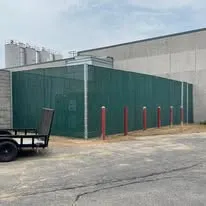 Commercial screen fence line along an industrial building edge with protected perimeter access.
