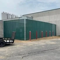 Commercial screen fence line along an industrial building edge with protected perimeter access.