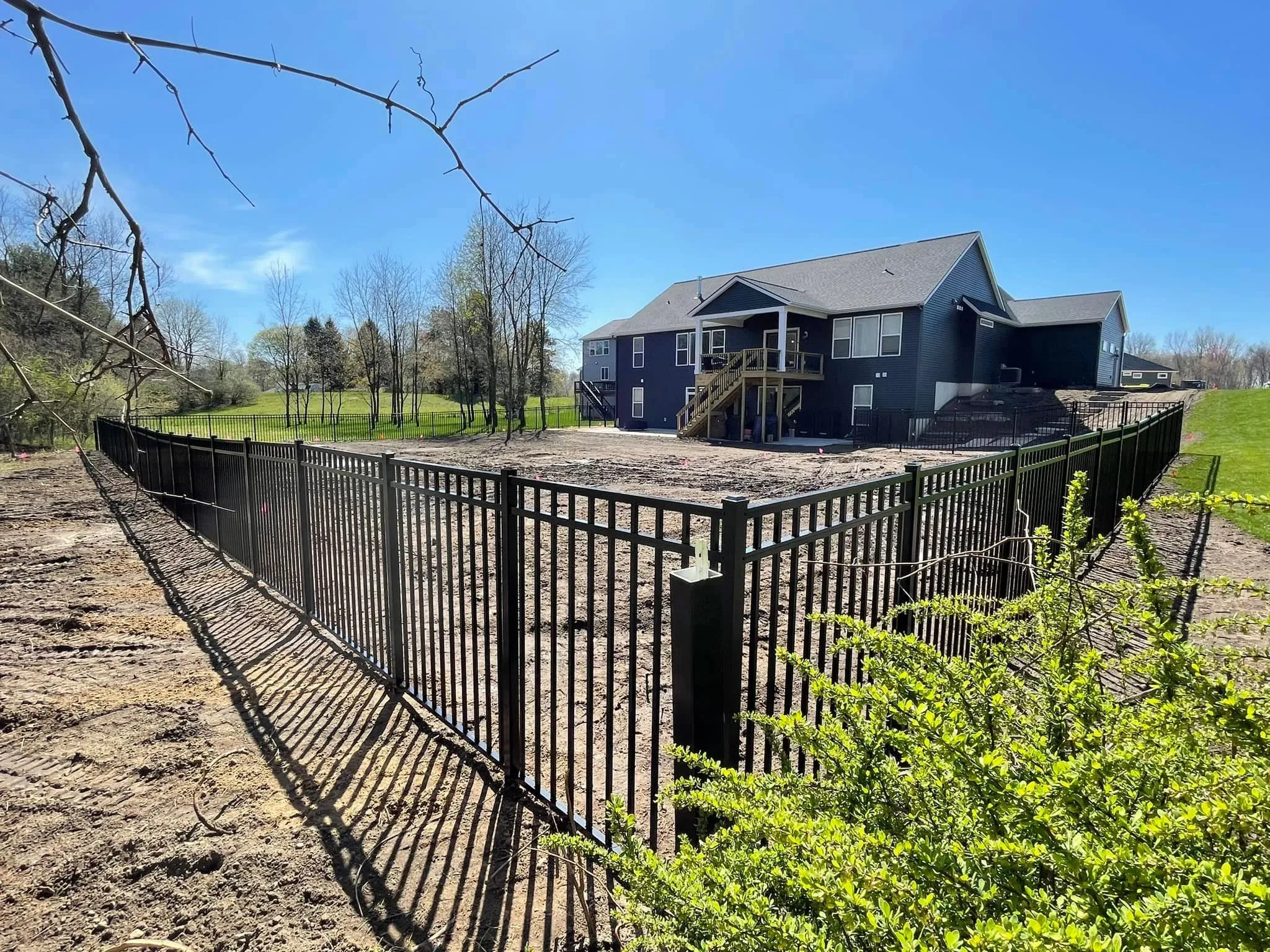 Black aluminum fence enclosing a wide yard corner with clean corners, straight runs, and an open look.