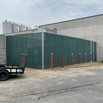 Commercial screen fence line along an industrial building edge with protected perimeter access.