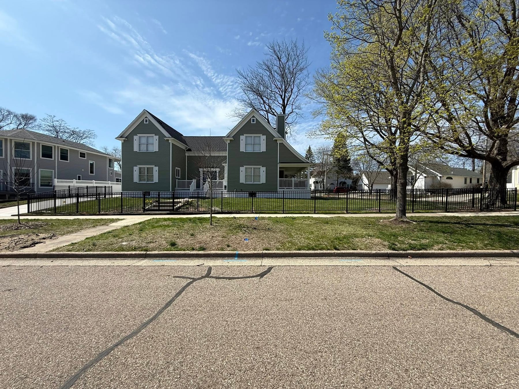 Black aluminum fence line across a front yard street view.