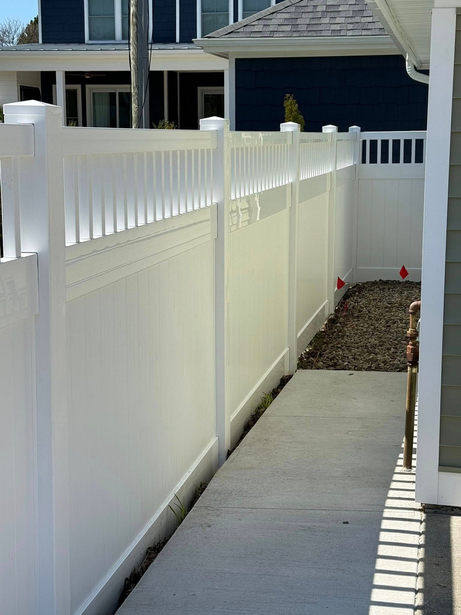 White vinyl fence line along a side-yard walkway.