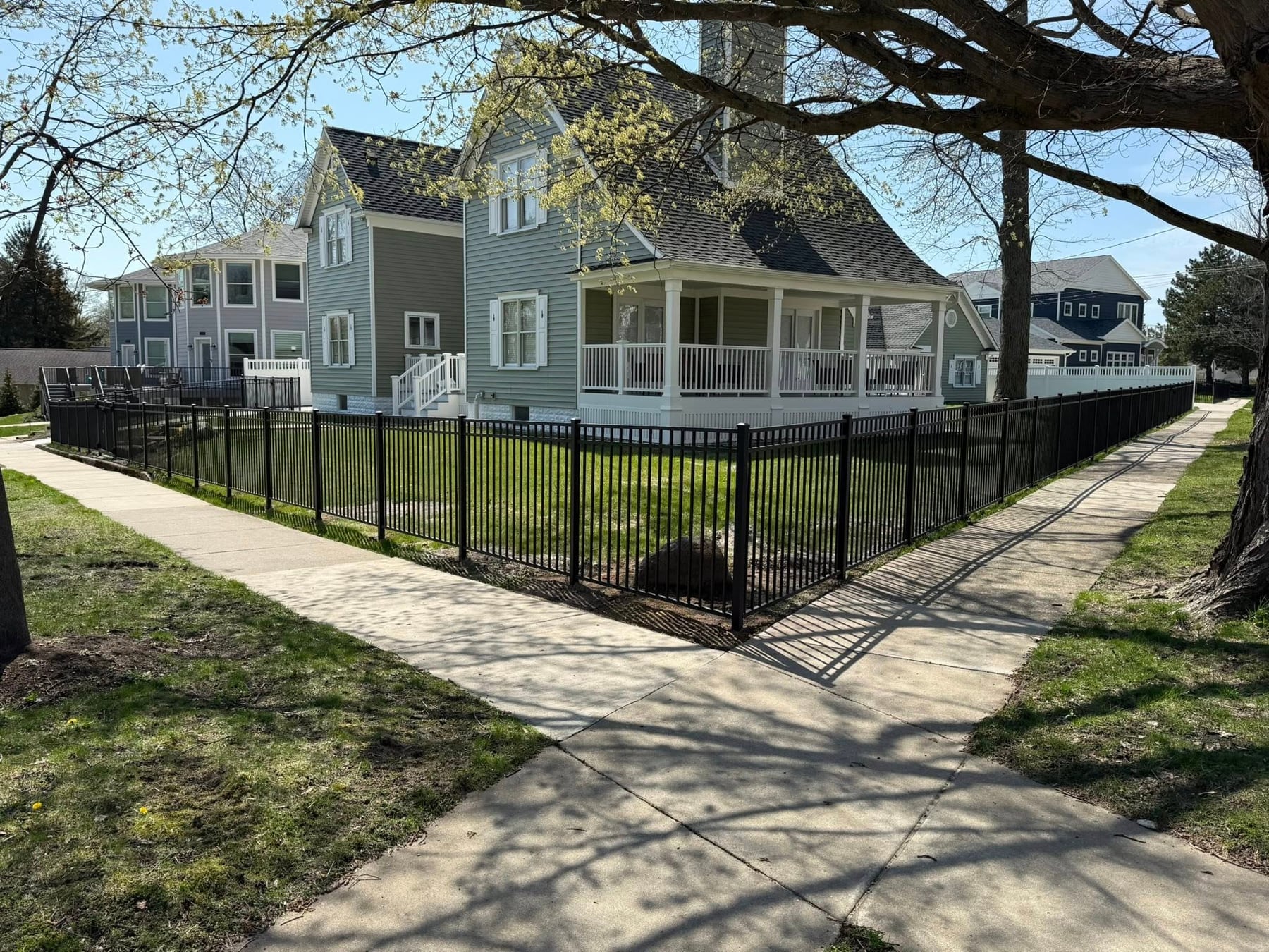Black aluminum fence line along a sidewalk with a clean corner layout and finished posts.