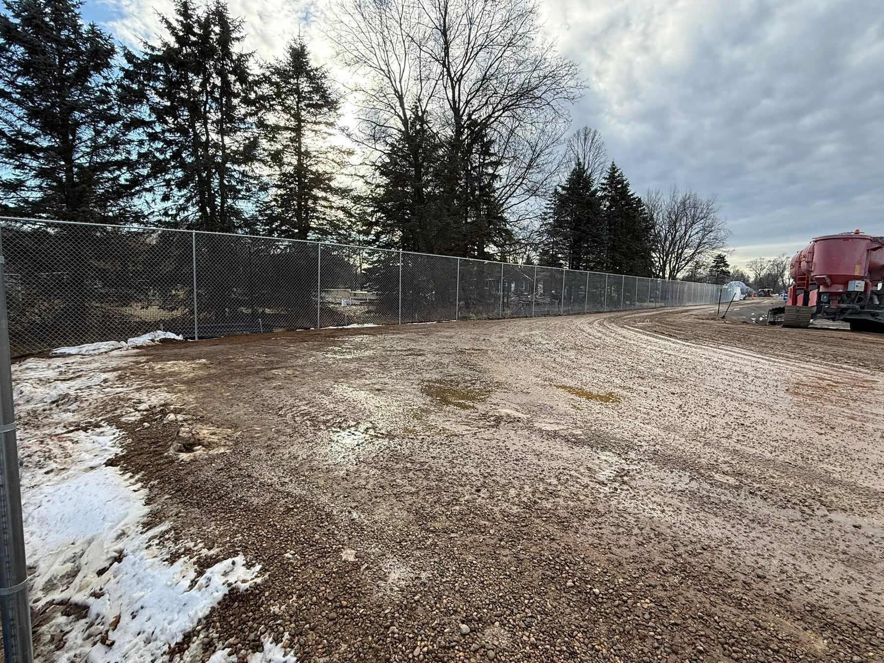 Chain link fence with privacy screen along a work area.