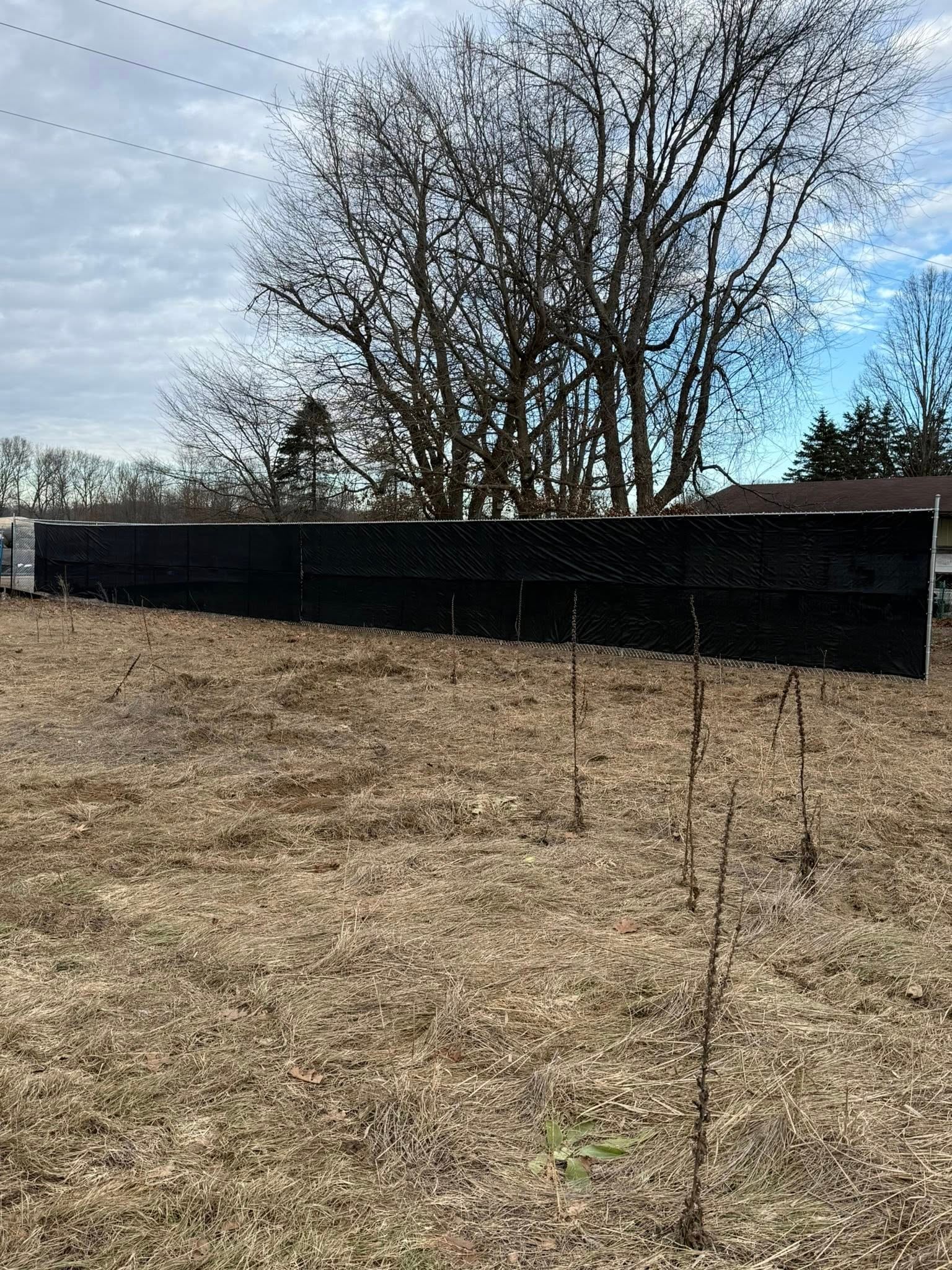 Chain link fence line along a gravel lot with winter conditions.