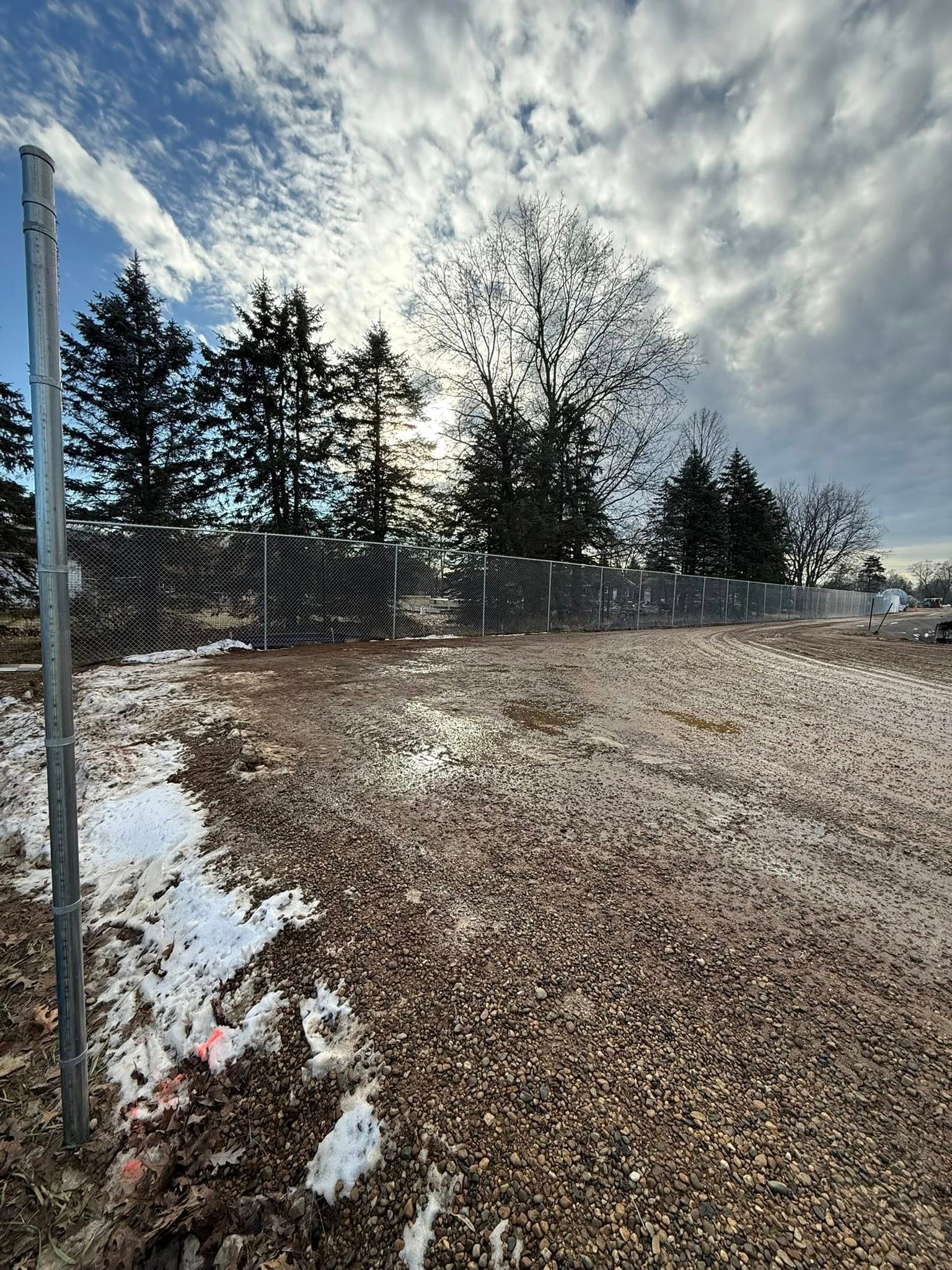 Privacy screen fence line along open ground in cold weather.