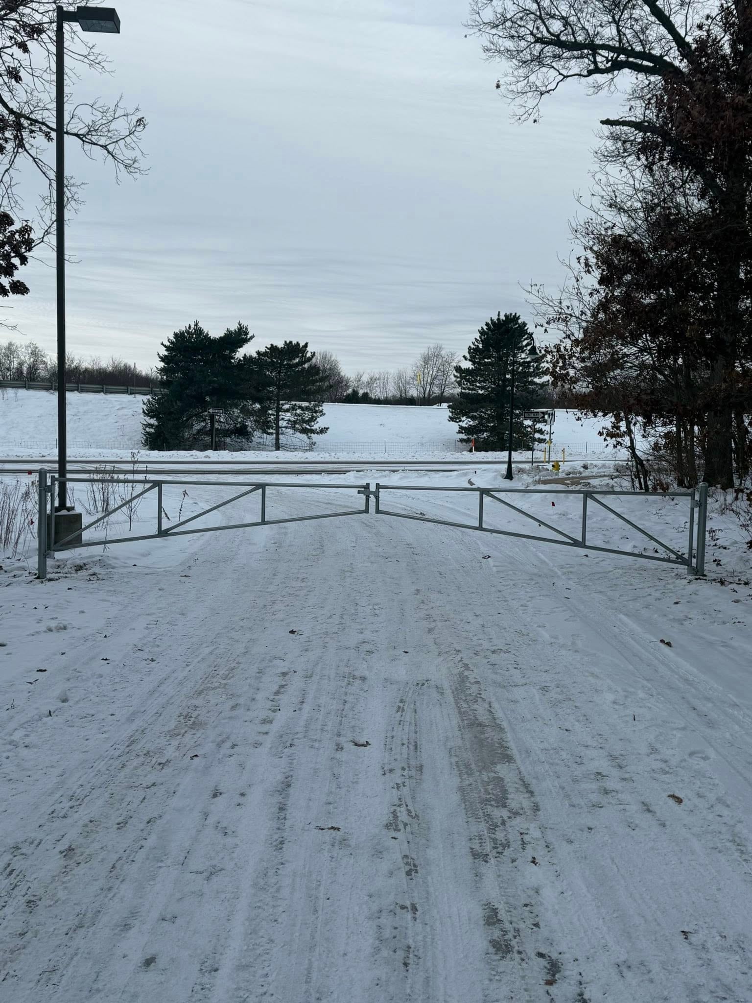 Long chain link fence line following a gravel road edge.