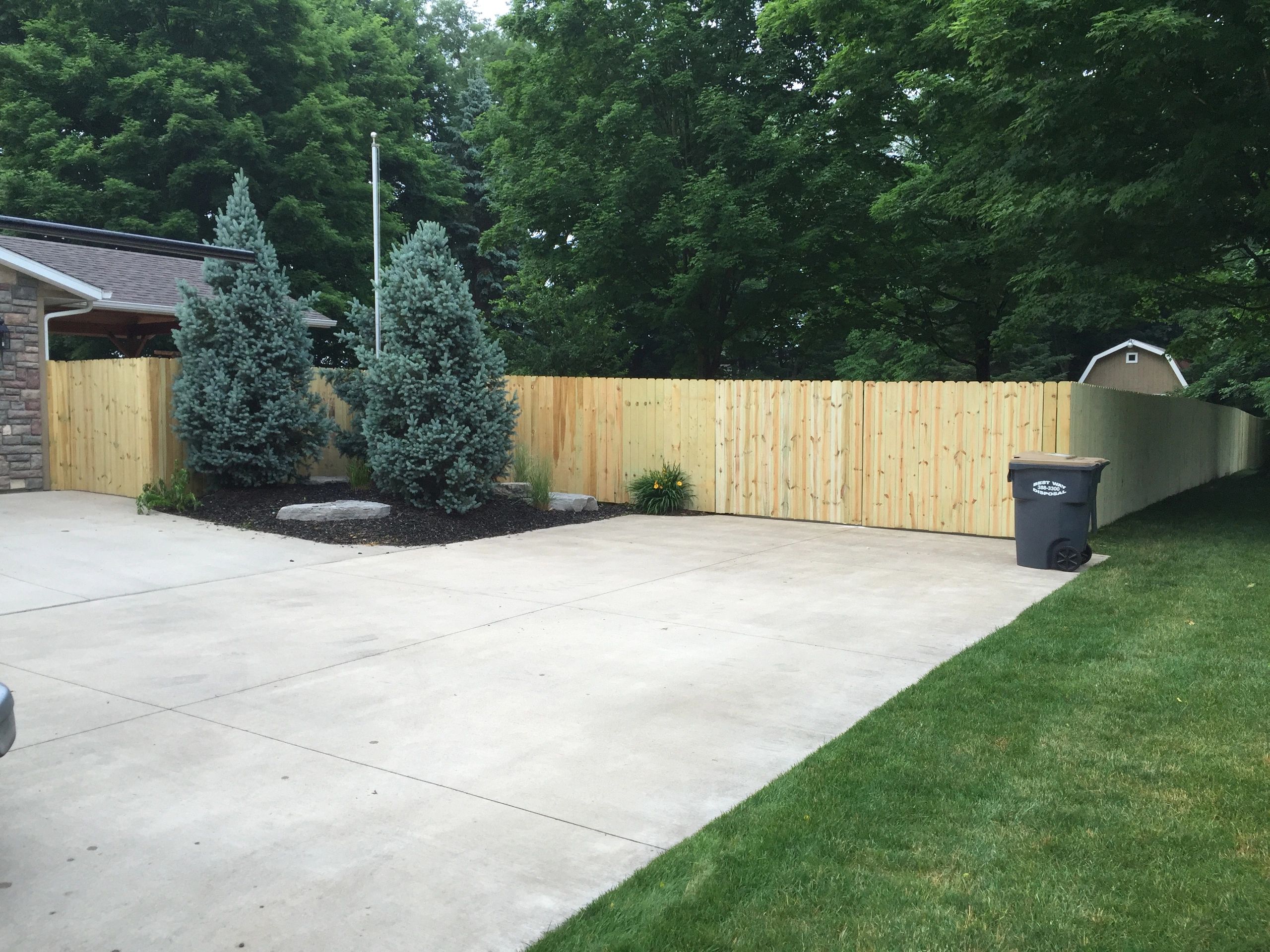 New privacy fence line along a driveway with clean spacing and a finished corner return.